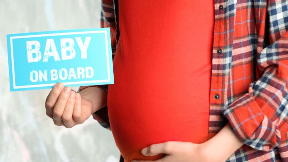 pregnant woman holding paper with baby on board