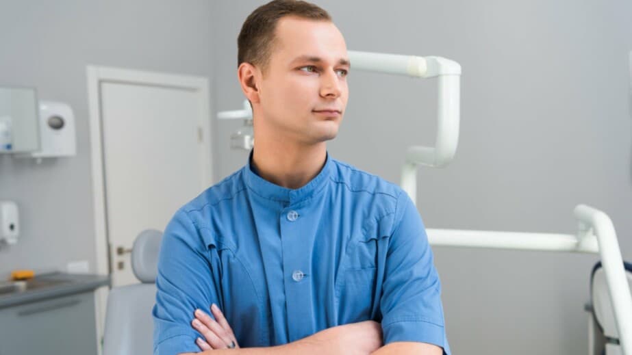 young dentist with crossed arms looking away